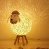 Veilleuse Bébé en forme de mouton posé sur une table en bois. 